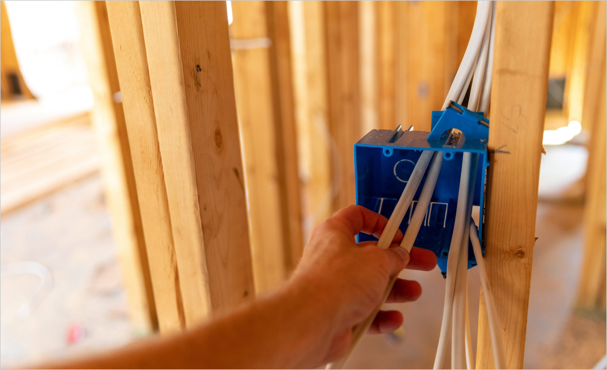 Electrical installation rough-in work showing professional installation of outlet box in construction framing during building process